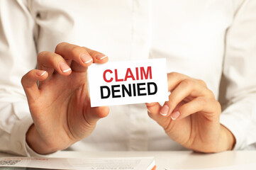 a woman in a white shirt holds a piece of paper with the text: claim denied. business concept