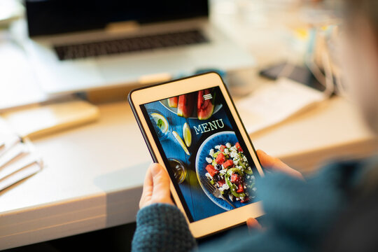 Woman Looking At Takeout Menu On Digital Tablet