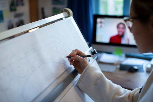 Female architect video conferencing and working at drafting table