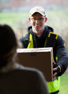 Friendly courier delivering package at front door