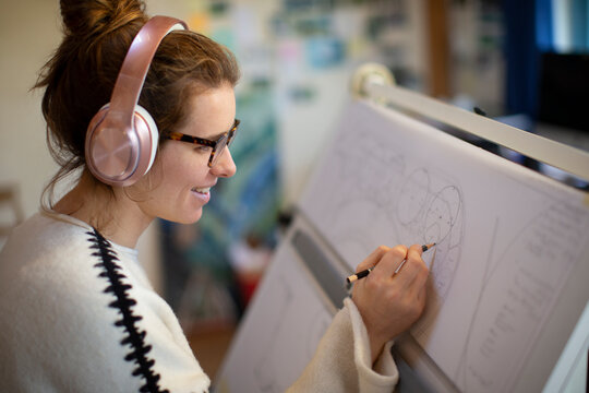 Female architect with headphones drafting blueprints