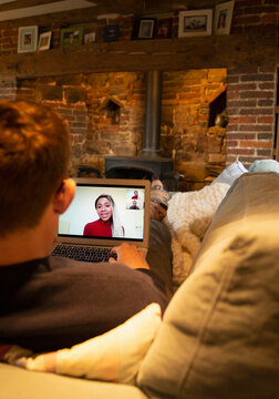 Man on sofa video conferencing with colleagues on laptop screen