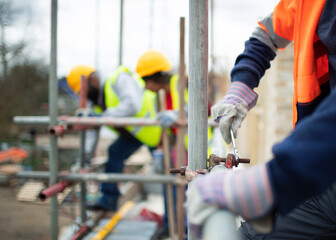 Construction workers assembling scaffolding at construction site