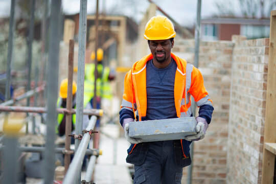 Male construction worker carrying brick at construction site