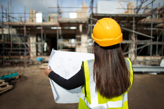 Female architect reviewing blueprints at construction site