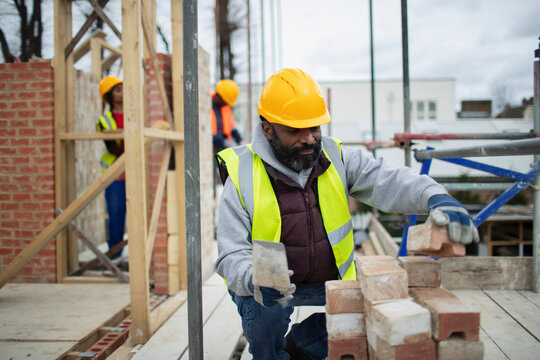 Male construction worker laying bricks at construction site