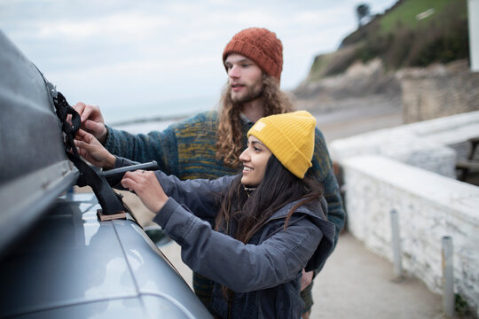Couple fastening rooftop cargo on car