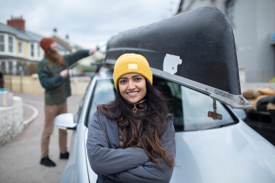Portrait happy young woman outside car with canoe