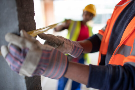 Close up construction workers using tape measure