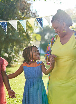 Happy grandmother and granddaughter in dresses in sunny summer park