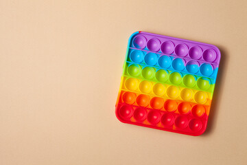 Rainbow silicone sensory antistress pop it toy on brown background. Top view.