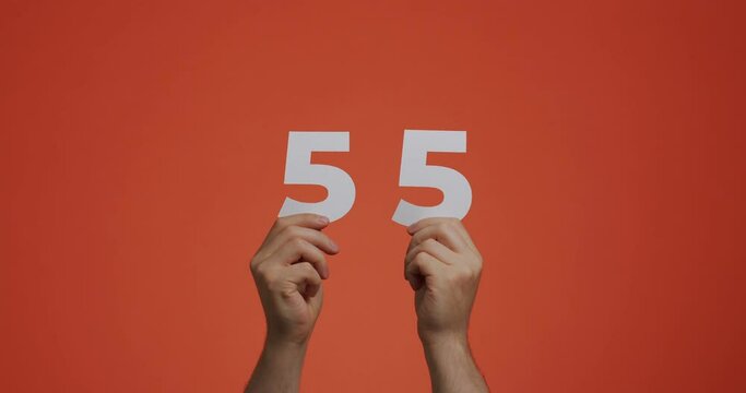 Number fifty-five in hands. Man showing digits, 55 made of carved paper for voting or mathematics learning