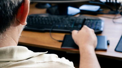 View of a man from behind working with a graphics tablet at his desk. Concept design and homeworking.