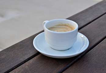A cup of coffee on a saucer on a brown wooden table