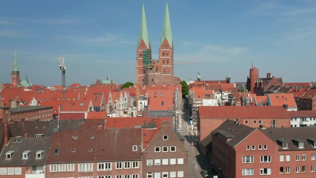 Sliding reveal of medieval city centre. Red brick buildings with red tiled roofs. Two tall towers of St. Marys church. Luebeck, Schleswig-Holstein, Germany