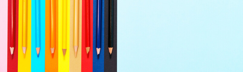 A set of colored pencils on a colorful background. A group of wooden colored pencils for drawing. Bright colors top view