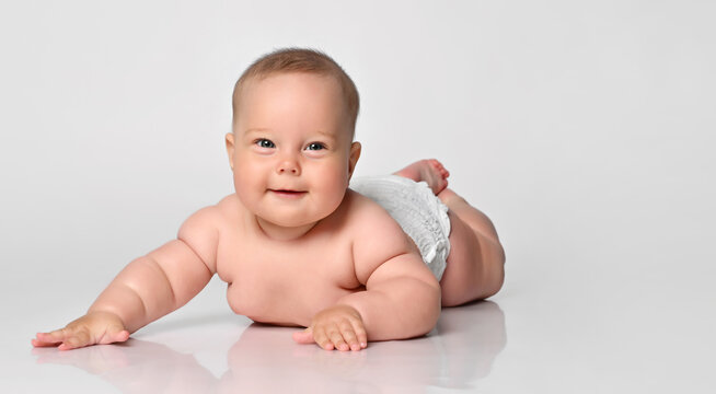 Happy portrait Six month old baby girl in a diaper lying looking at you, arms outstretched to the sides. on white background