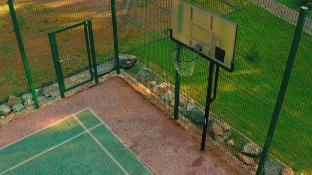 Top view of basketball player approaching, scoring hoop during workout on basketball court outdoor in sunlight