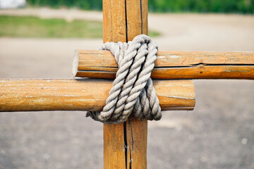 Close-up fragment of wooden fence. Wooden logs tied with strong rope. - Powered by Adobe