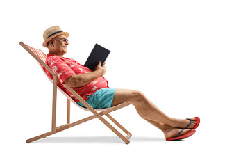 Mature male tourist reading a book and sitting in a bech chair