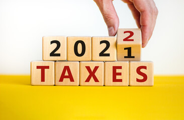 Business concept of taxes planning 2022. Businessman turns wooden cube and changes words 'Taxes 2021' to 'Taxes 2022'. Beautiful white background, copy space. Business, 2022 taxes concept.