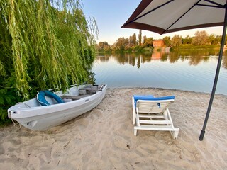 River bank sun chairs and umbrellas by the river. Peaceful summer morning by the river bank. 
