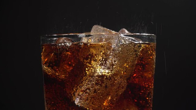 Vaso girando con refresco de cola con hielos