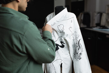 partial view of blurred fashion designer near kimono with traditional drawing on mannequin