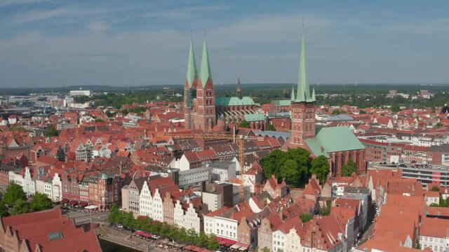 Forwards fly towards historic brick buildings in medieval city centre. North German brick gothic churches. Luebeck, Schleswig-Holstein, Germany