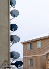 Vertical Parabolic satellite dishes and electricity meters on exterior wall of building
