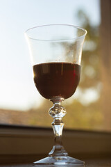 Closeup of a glass of wine on a window sill on a summer evening.