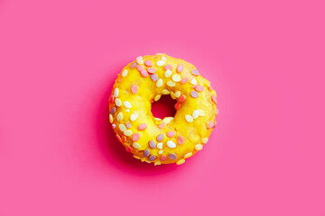 Yellow sugar glazed donut on colorful purple background.