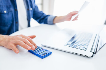Close-up of hands that calculates with a calculator to manage household finances at home, a man...