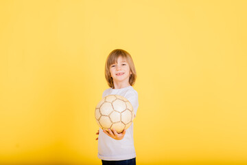 Portrait of boy holding soccer ball, studio yellow background