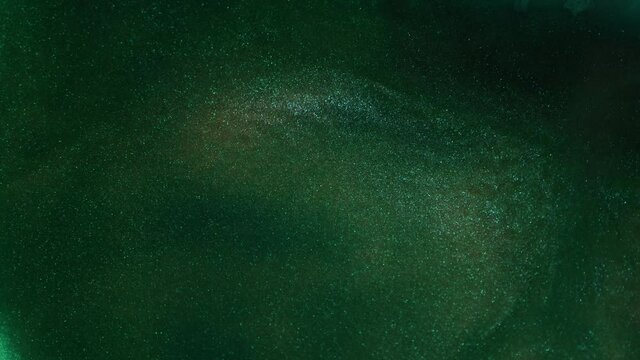Flowing glitter waving surface. Flowing Golden abstract backdrop. Beautiful metallic green texture paint close-up. Liquid slow motion Art. Colorful Chaos Turbulence. 