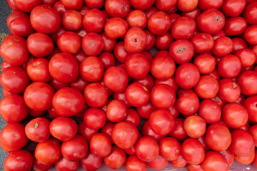 Red ripe tomatoes in flat pile for sale.