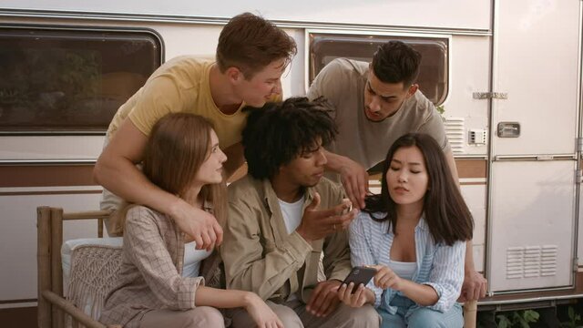 Group Of Young Multiracial Friends Using Smartphone Together While Relaxing At Camping