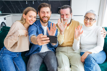 A cheerful family with a small child sitting on the couch, having fun on the Internet, using the application, talk via video link with relatives.