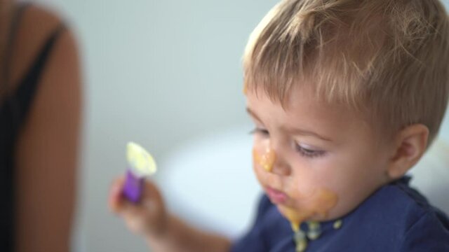 Baby boy eating porridge with dirty face