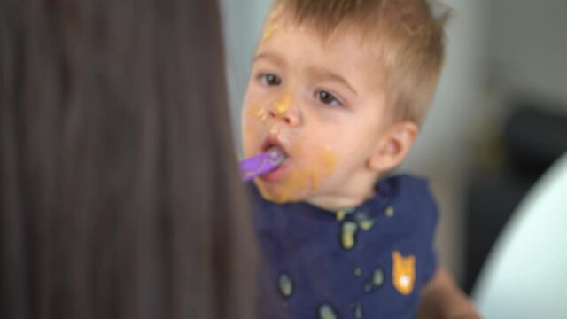 Baby boy eating porridge with dirty face