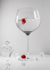 scarlet raspberries fall into a glass of water