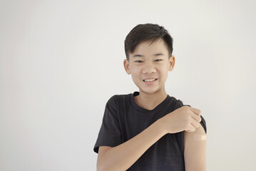 Mixed Asian teen boy showing his arm with bandage after got vaccinated or  inoculation, child...