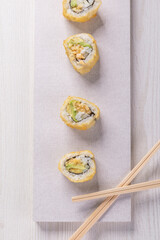 detail of a gourmet plate with sushi rolls with some wooden chopsticks, food texture in studio, traditional dish