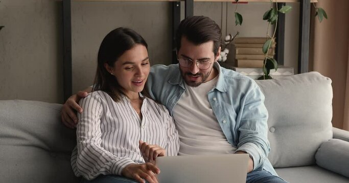 Bonding happy young family couple looking at laptop screen, reading email with amazing news, celebrating winning online lottery or giveaway, getting bank loan mortgage approvement, victory concept.