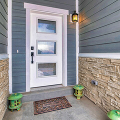 Square White front door with glass panes at home entrance with lanterns on the doorstep