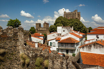 View towards the tower of „Castelo de Bragança“ castle surrounded by white houses with red...