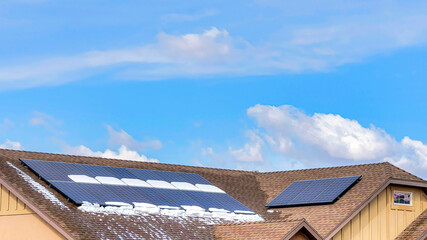 Pano Focus on the snow dusted and wet roof of a house with installed solar panels