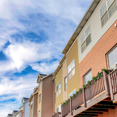 Square Townhouses with balconies over garages against Wasatch mountain and cloudy sky