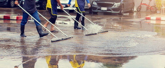 Selective focus to worker using wiper or squeegee to clean floor surface. Staff cleaning floor with...