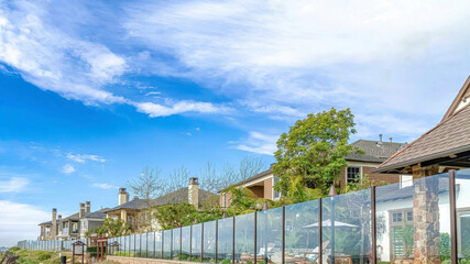 Pano Pathway along homes with glass fences under skyscape of blue sky and clouds
